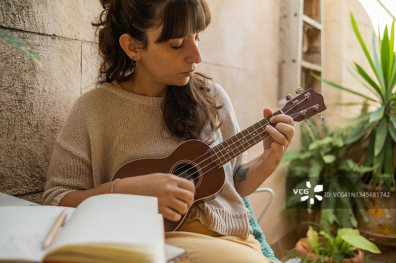 在露台上弹尤克里里的年轻女孩图片素材