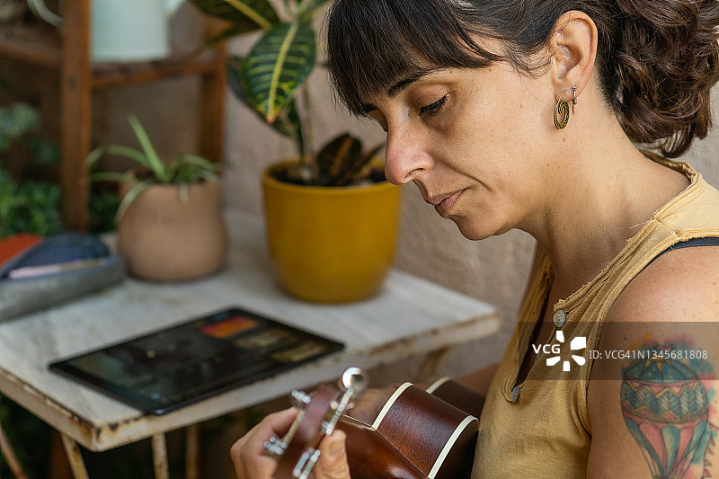 在业余时间弹奏尤克里里的年轻家庭主妇图片素材