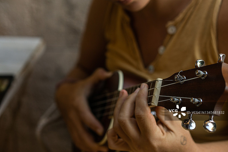 30多岁的女人喜欢用夏威夷尤克里里弹奏音乐图片素材