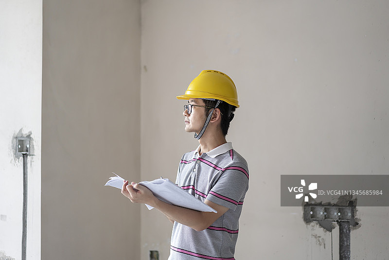 亚洲男工程师在改造工地使用建筑图纸工作图片素材