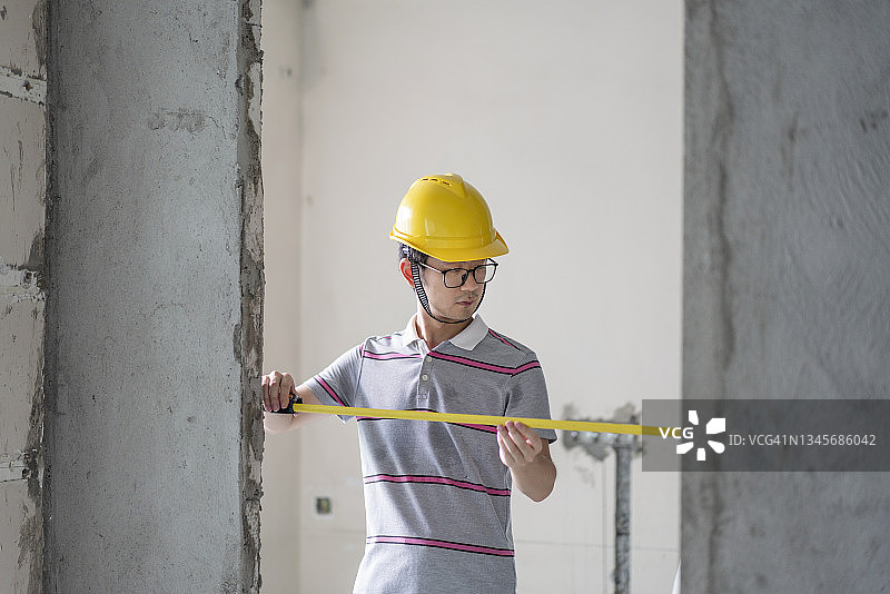 在装修工地戴着头盔工作的亚裔男工程师图片素材