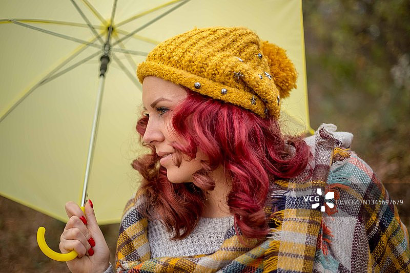 女子在公园里撑着黄色雨伞图片素材