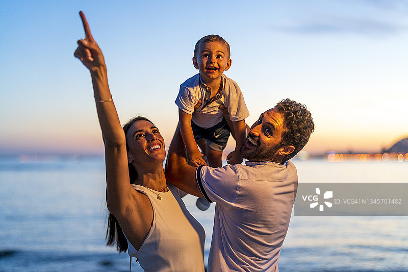 快乐的中年夫妇和儿子在海滩上玩耍图片素材
