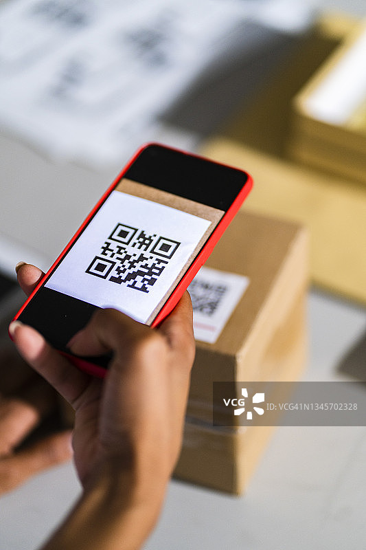 女商人用智能手机扫描包裹条形码图片素材