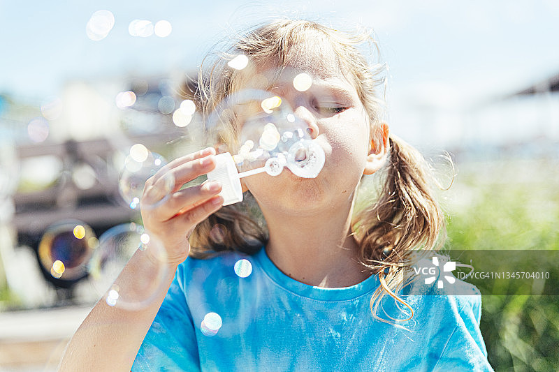 在阳光明媚的日子里，女孩用魔杖吹泡泡图片素材