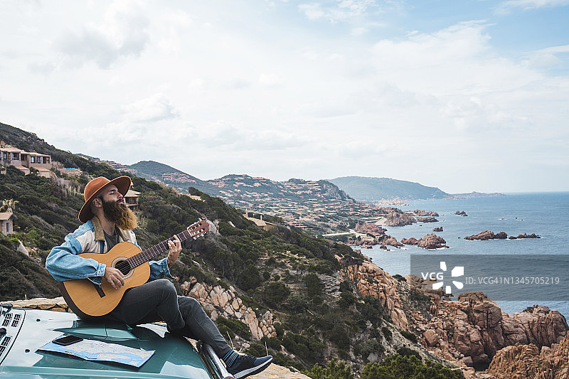 男人坐在汽车引擎盖上弹吉他图片素材