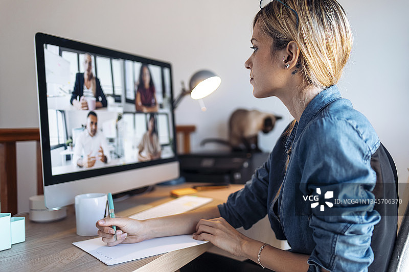 女人在家中参加视频会议并做笔记图片素材