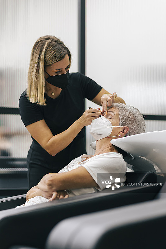 戴着口罩的女美容师在美容院为顾客修眉图片素材