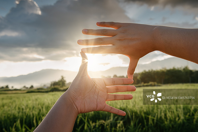 女性伸出手触摸日落时山脉的风景（特写）图片素材