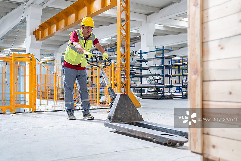 仓库工人使用托盘车搬运工厂仓库中的库存图片素材