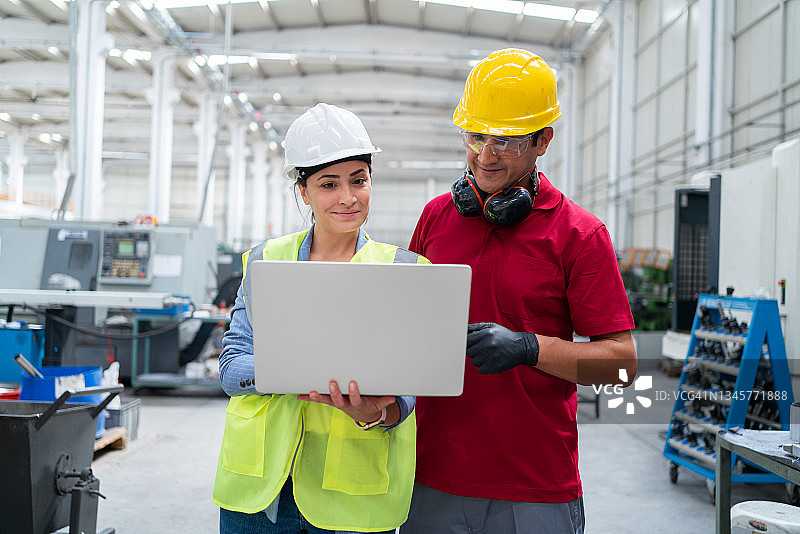 女性工程师和工人在工厂用笔记本电脑讨论生产图片素材