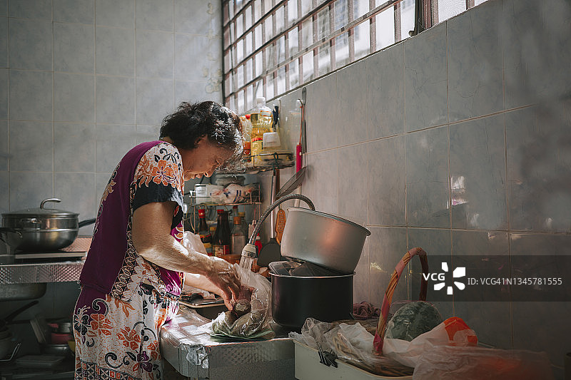 亚洲的中国妇女准备食物在厨房做饭在水槽清洗鱼图片素材