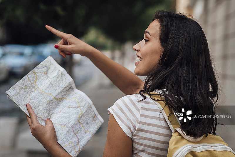 年轻女人在城市中行走，查看地图并观光图片素材