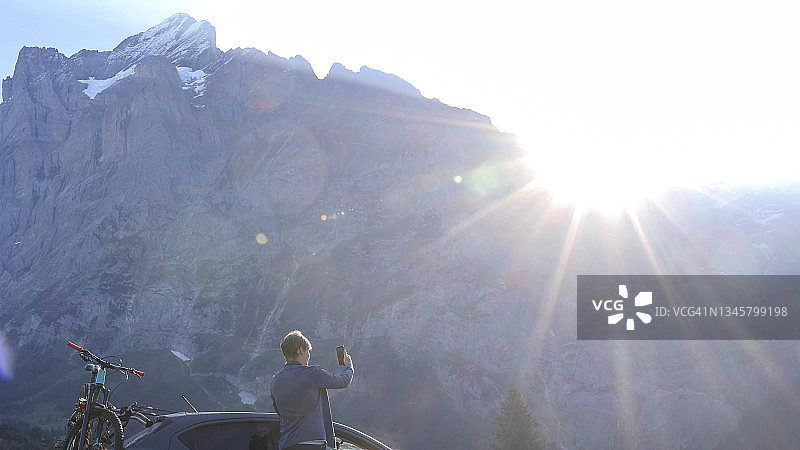 年轻男人在绿草如茵的草地上在车外放松图片素材