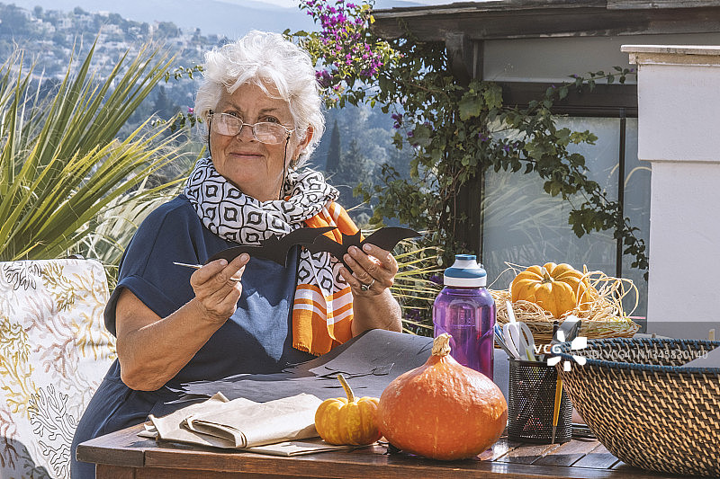 女人面带微笑，看着镜头准备万圣节装饰品图片素材