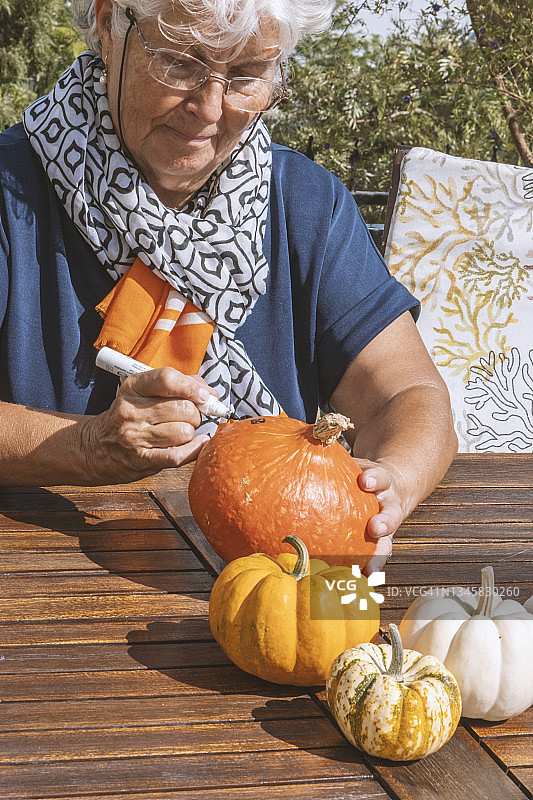 年长的女人在万圣节南瓜上绘画图片素材