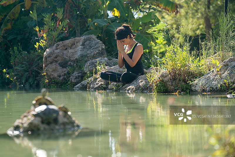 在池塘边做瑜伽的成年女人图片素材