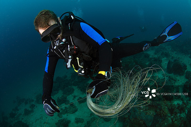水肺潜水员从渔线中释放珊瑚图片素材