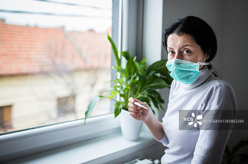 年轻女人在看温度计，她发烧了图片素材