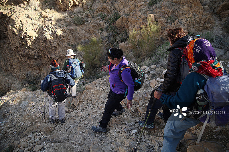 老年徒步者在犹太沙漠中具有挑战性的徒步旅行中下降陡峭的斜坡图片素材