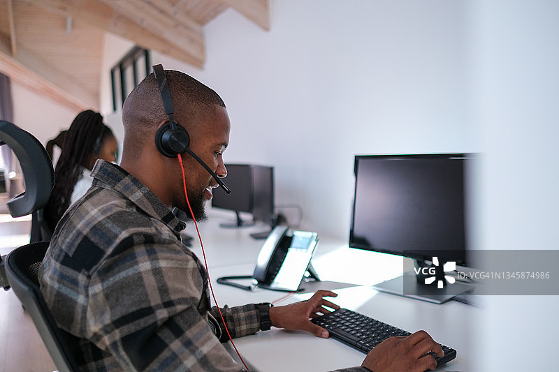 戴着耳机用电脑工作的非洲男人图片素材