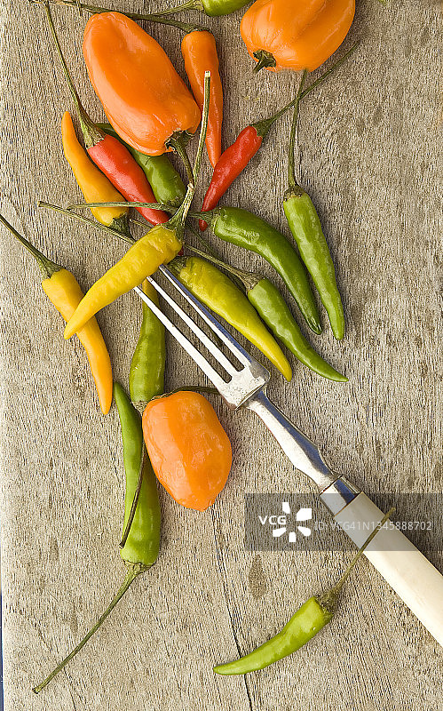 风化木背景上的各种辣椒和叉子图片素材