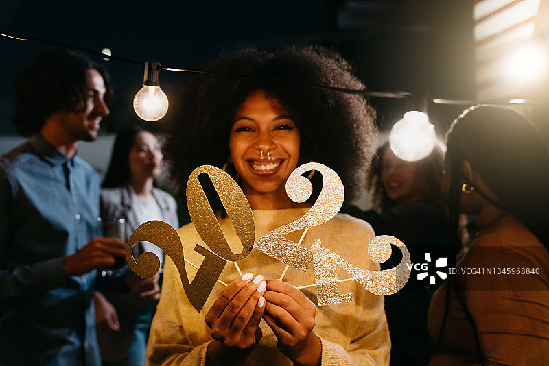 非裔发型女子手持2022数字闪片庆祝新年图片素材