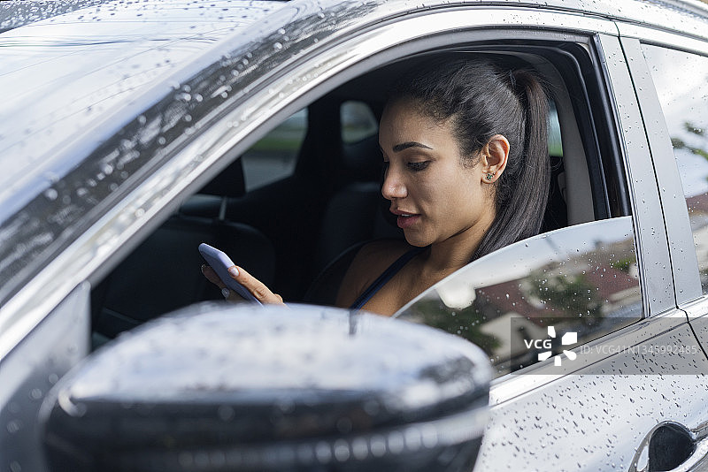 拉丁裔女人在车里用手机写字图片素材