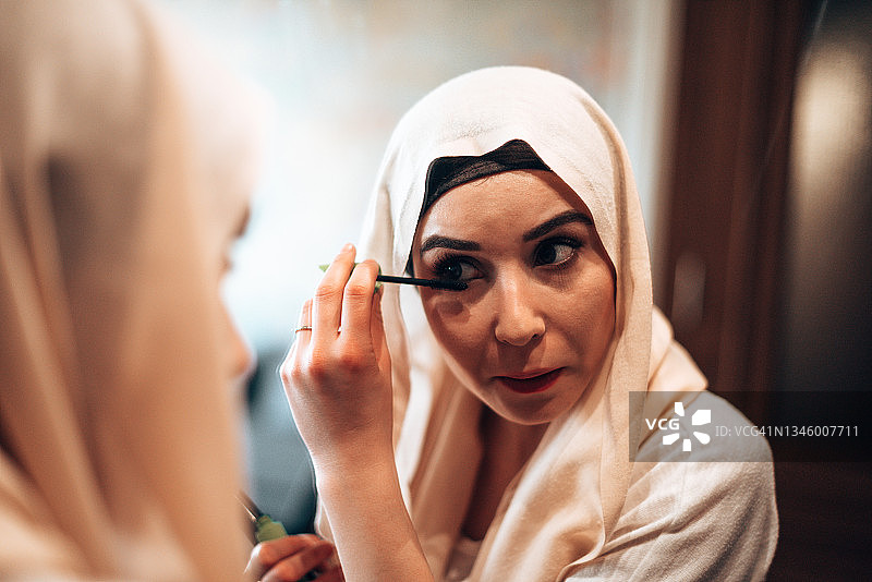 在镜子前化妆的穆斯林妇女图片素材