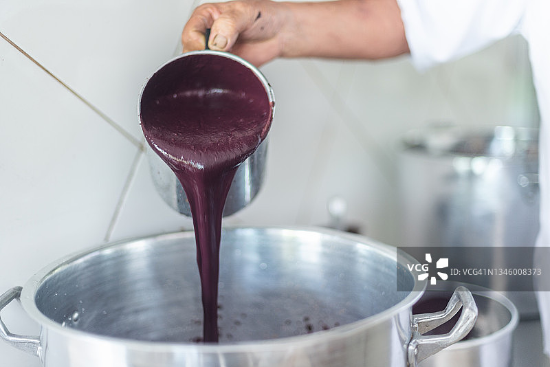工人将刚提取的新鲜巴西莓果肉倒入锅中图片素材