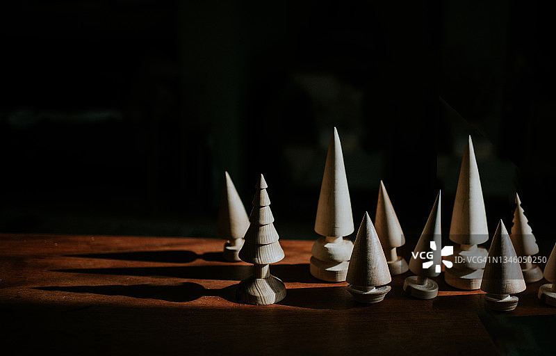 木质表面上投下长长阴影的各种手工木制小树图片素材