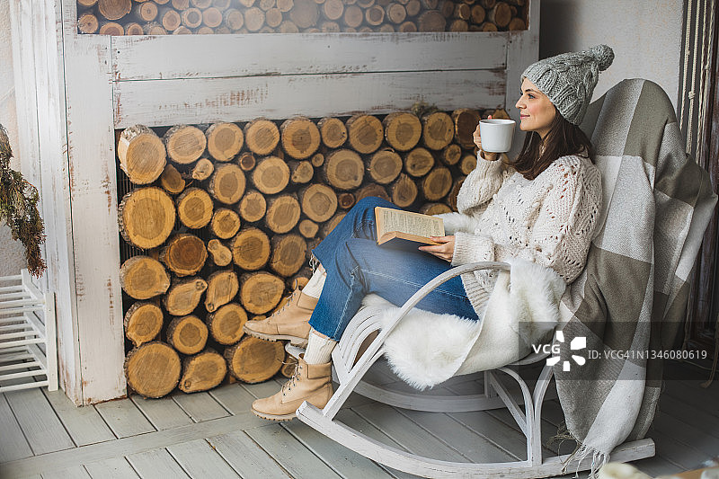 冬天，在家里阳台上读书喝热饮的女人图片素材