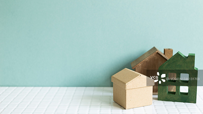 白色瓷砖桌面上的房屋模型，薄荷色背景，房地产概念图片素材