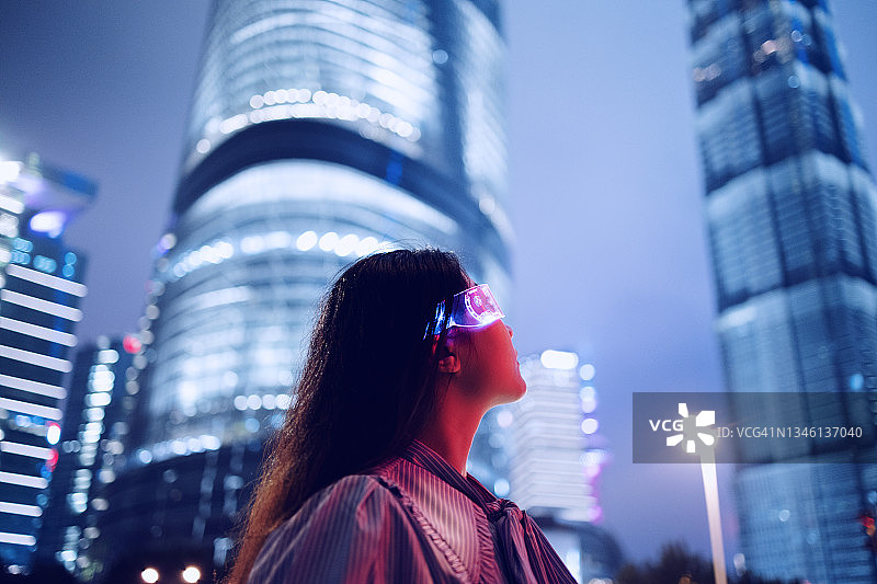 年轻女商人站在市中心金融区，背景是现代金融摩天大楼图片素材