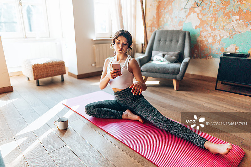 在家做瑜伽和发短信的女人图片素材
