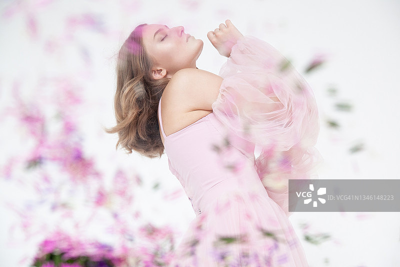 身穿粉色连衣裙，手捧鲜花的柔和女人图片素材