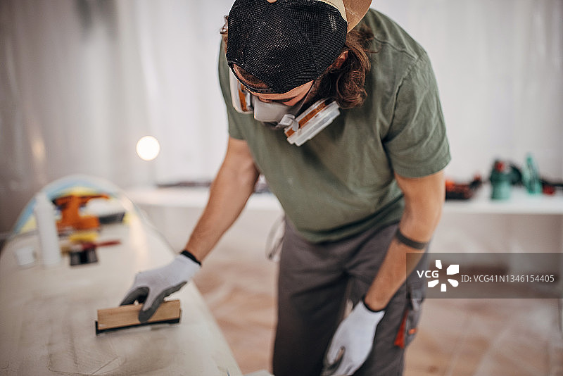 给冲浪板打蜡的男人图片素材
