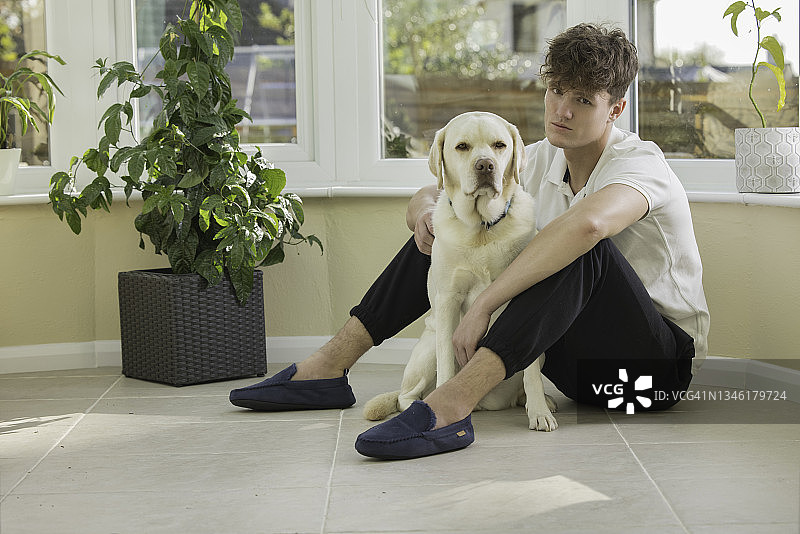 年轻男人和他的狗在他的温室里图片素材