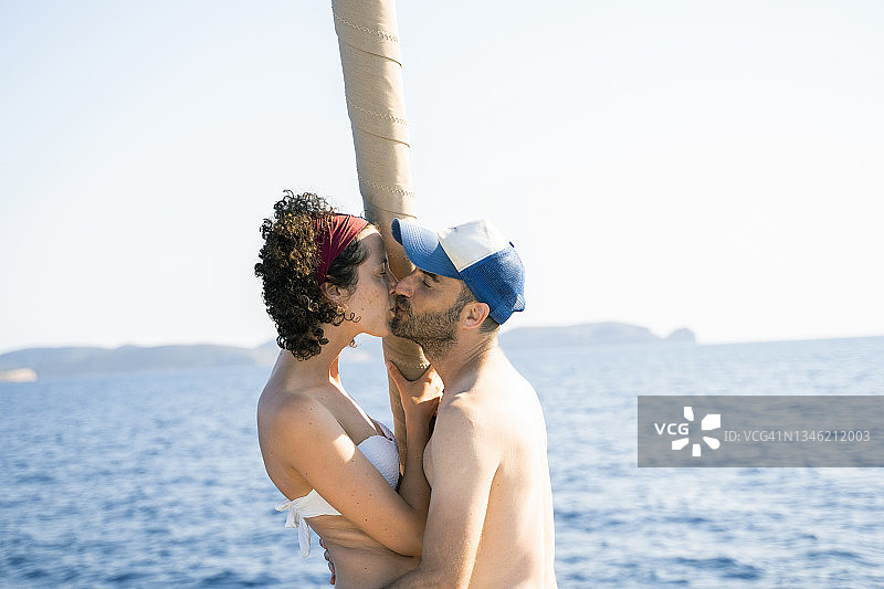 情侣在航船边缘亲吻，以大海为背景图片素材