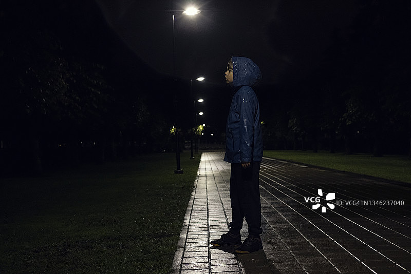 站在黑暗阴雨中的男孩图片素材