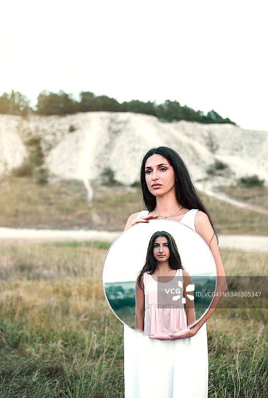 美丽的亚洲女人拿着一面镜子，镜子里映出她在户外的女儿图片素材