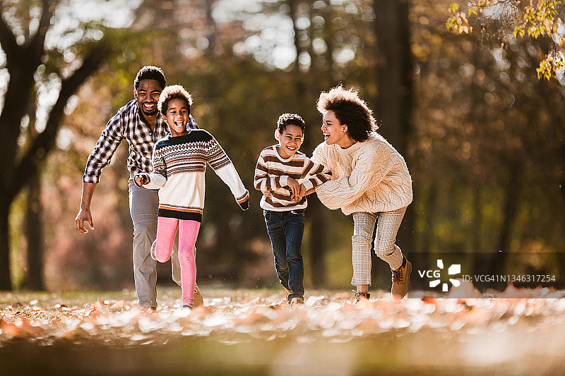 快乐的非裔美国家庭在公园里追逐图片素材
