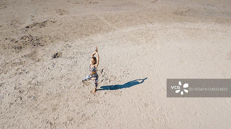 无人机视角：女子在沙滩上练习瑜伽，留下美丽的倒影图片素材