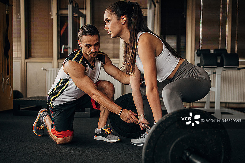 私人教练协助一位女士进行举重图片素材