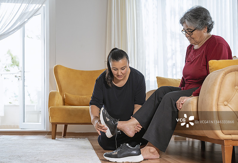 女人在家帮年迈的母亲穿鞋图片素材