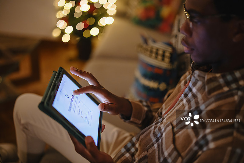 年轻男人在他的平板电脑上进行在线圣诞购物图片素材