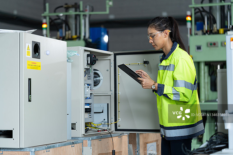 女技术员或电气工程师检测保险丝柜中的电线电压，工人在工厂检查工程自动化机器图片素材