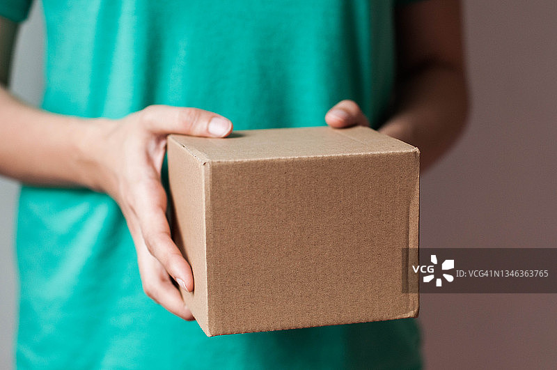 年轻东南亚女人在室内手持纸箱包裹图片素材