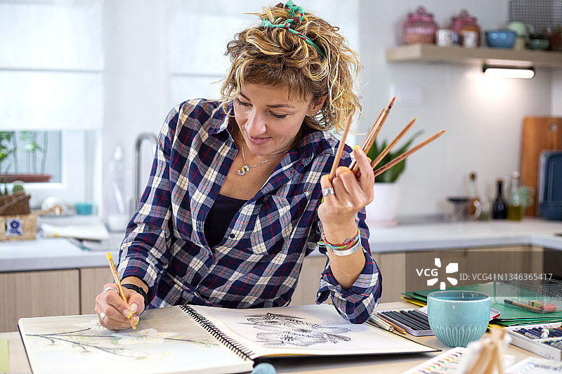 迷人的女人在笔记本上用铅笔画画图片素材