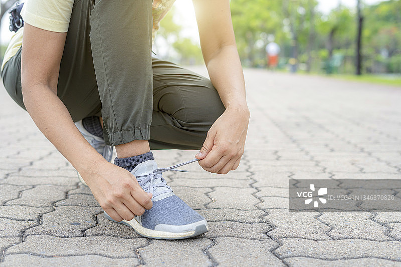 健壮的白人女人在球场上跪着系鞋带的特写图片素材